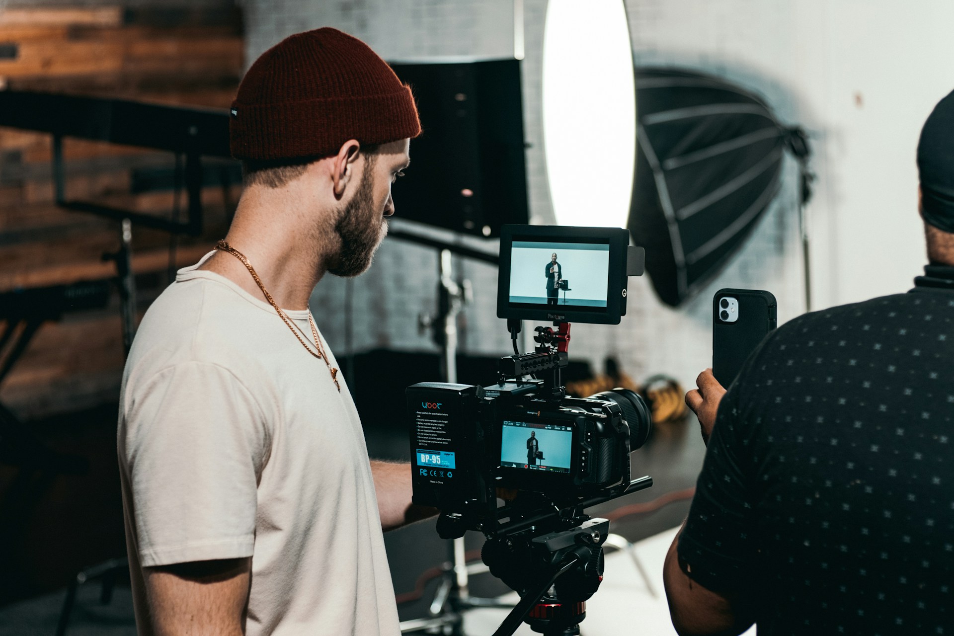 Behind-the-scenes testimonial video production setup with a videographer, professional camera, lighting and interview recording equipment.